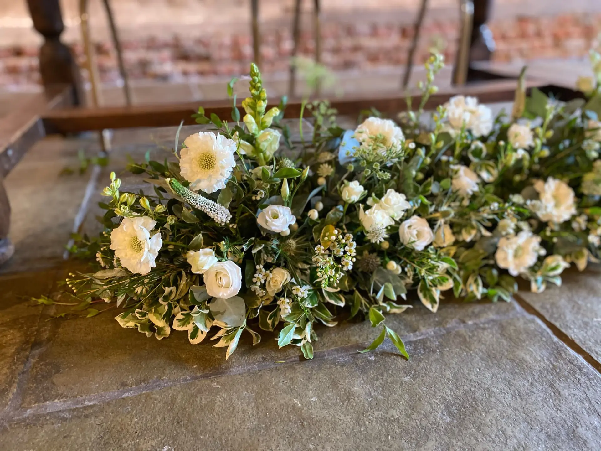 Meadow-style floral table runner of white scabiosa, spray roses and greenery