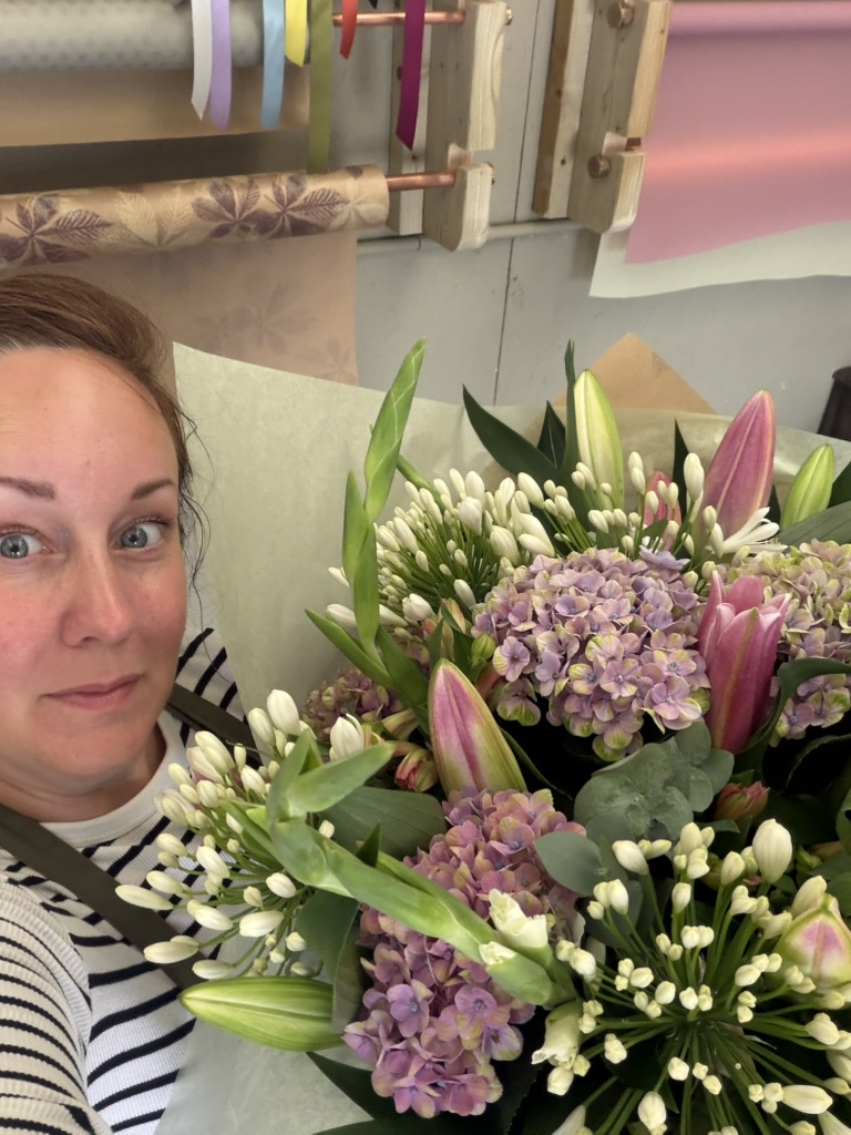 Rachel Emmerson holding a bouquet of hydrangeas, lilies and eucalyptus at her flower studio in King's Lynn