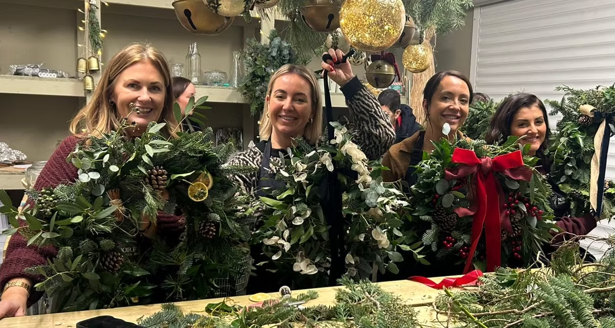 Guests holding their finished Christmas wreaths at a Norfolk Flower Boutique workshop