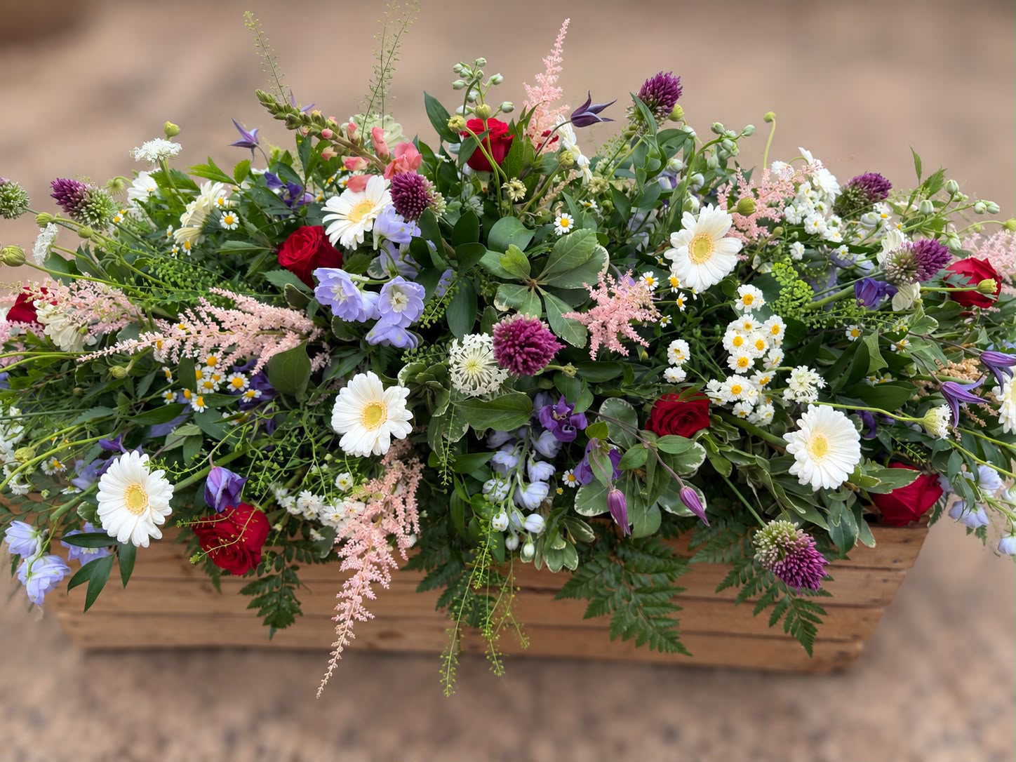 Country meadow style tribute spray with daisies, roses and astilbe