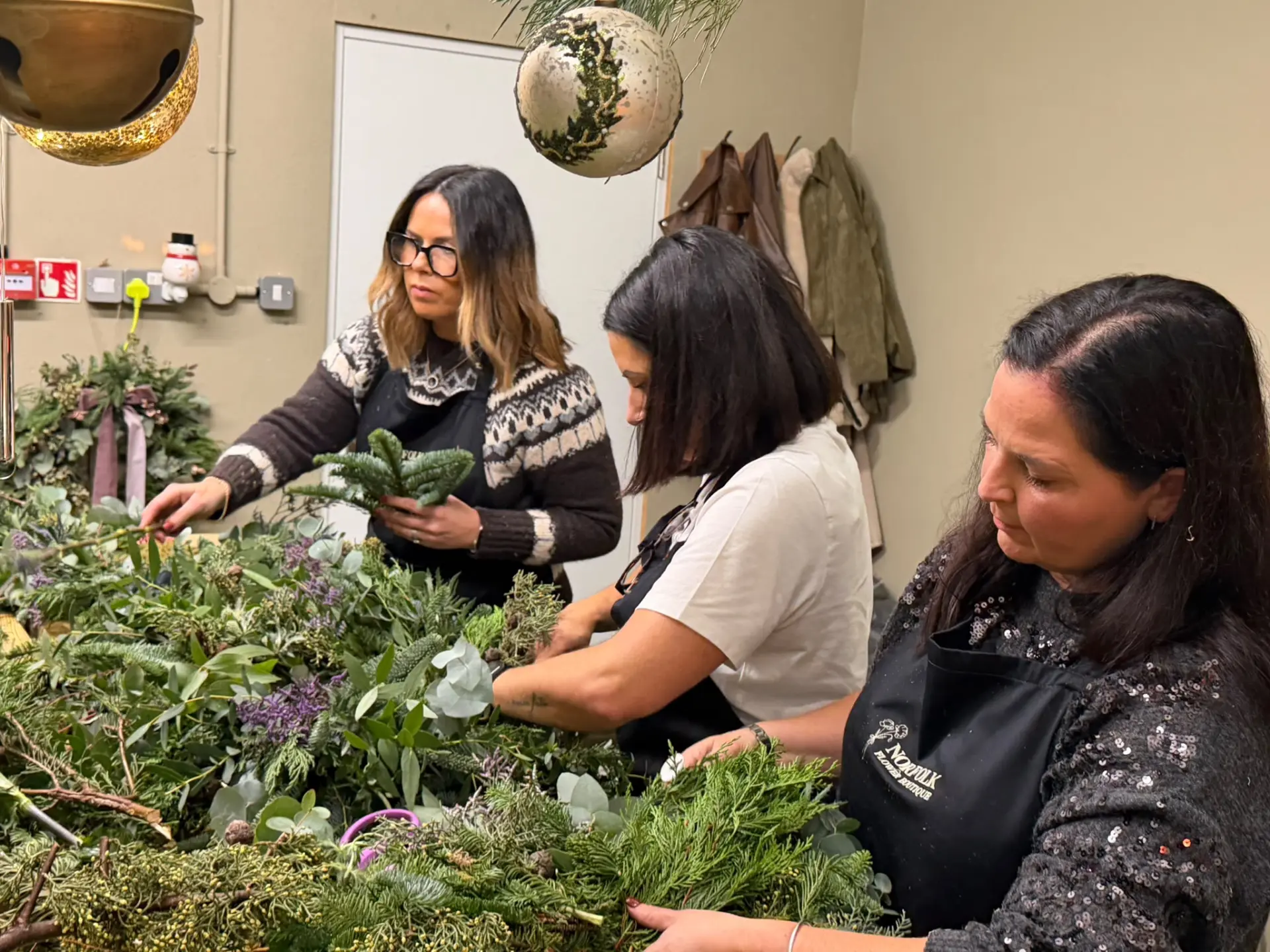 Guests building fresh evergreen wreaths together at a workshop table