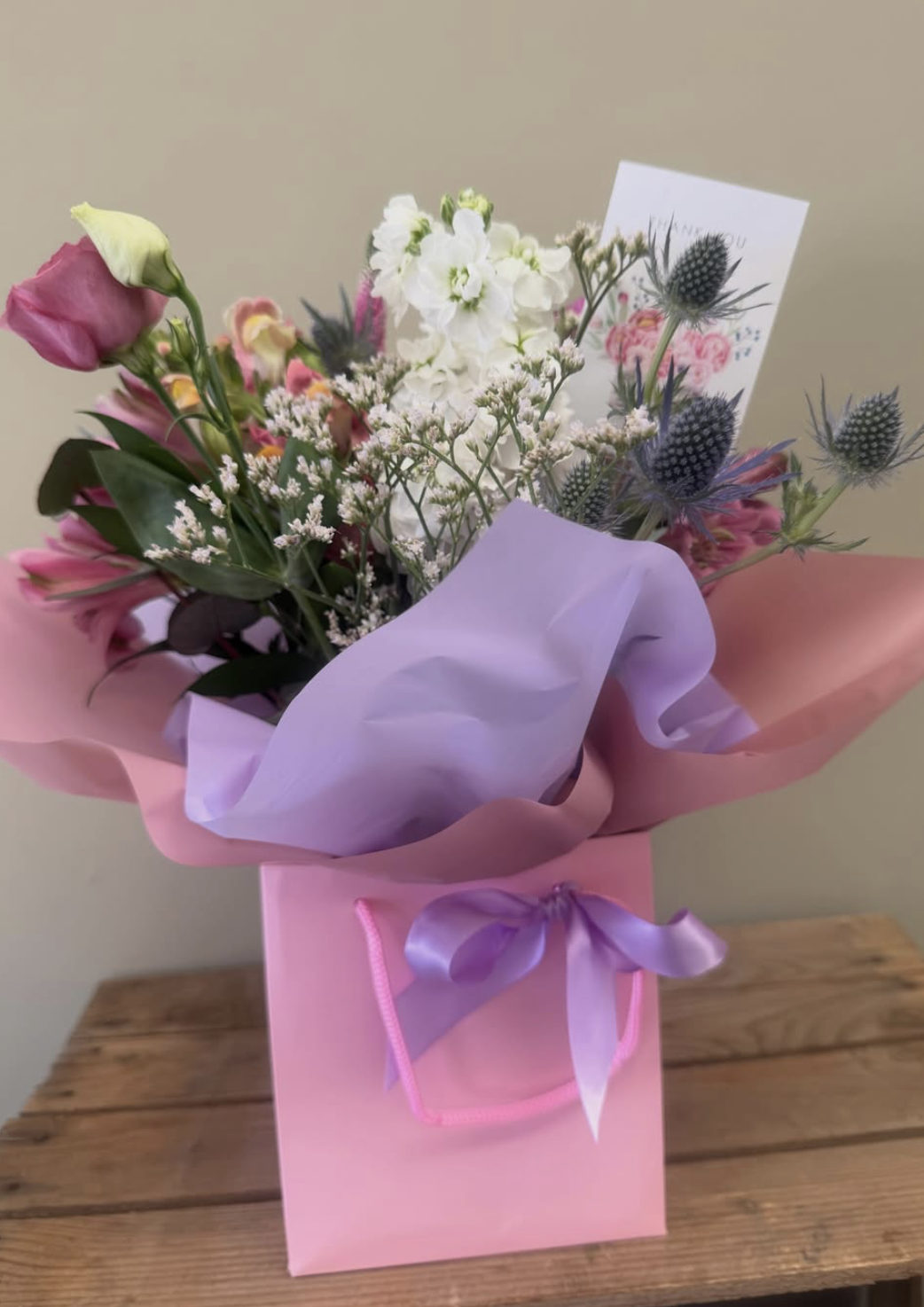 Pink and lilac gift bouquet with stocks, thistle and lisianthus in a pink gift bag