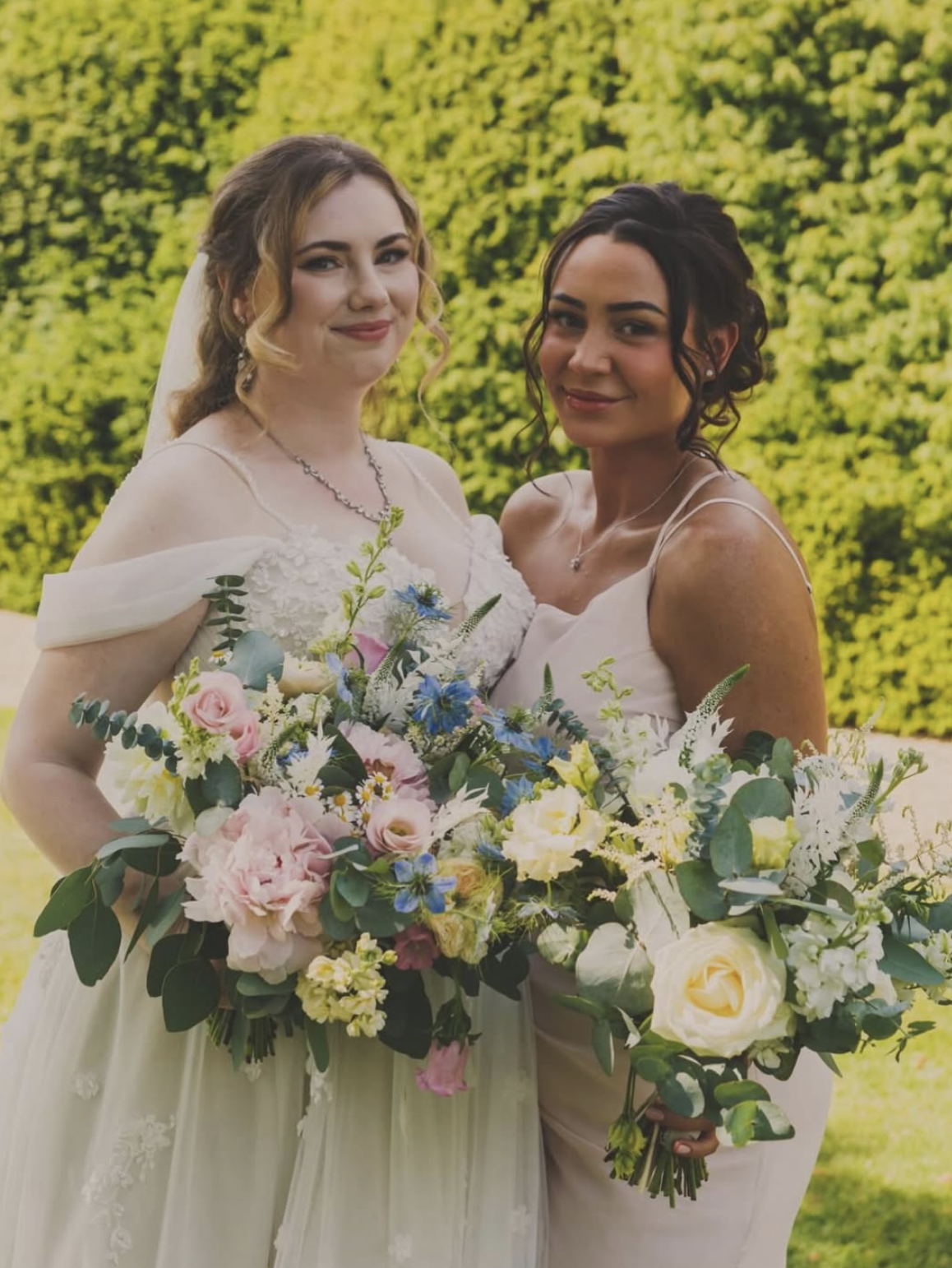 Bride and bridesmaid holding blush, blue and ivory garden-style bouquets