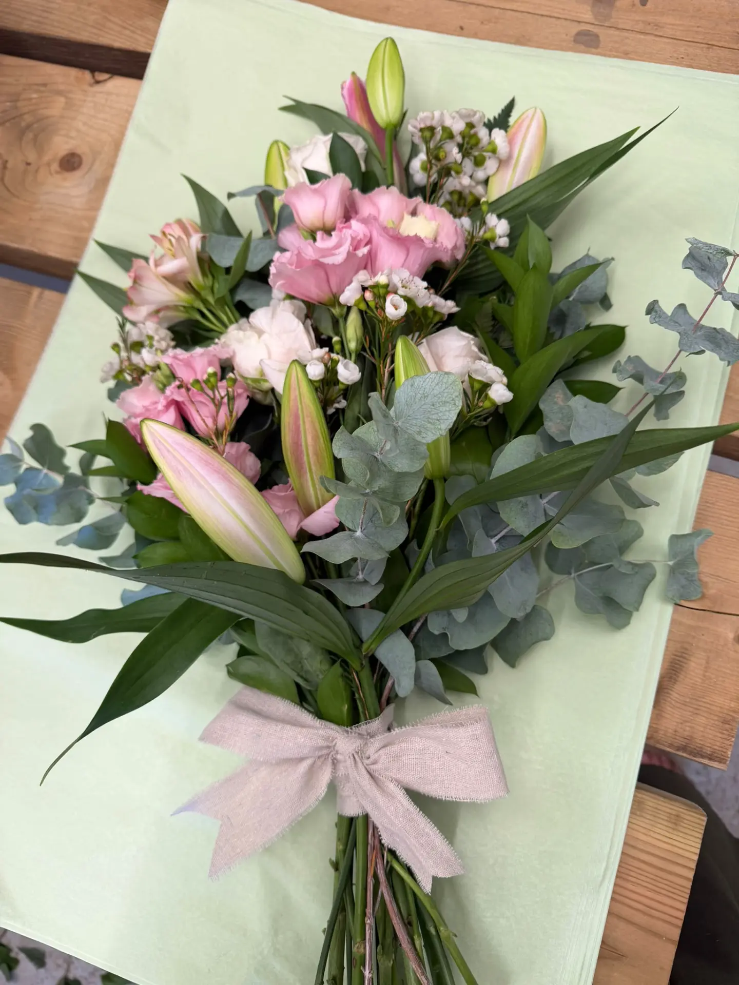 Pink lisianthus and lily tied sheaf with a linen ribbon