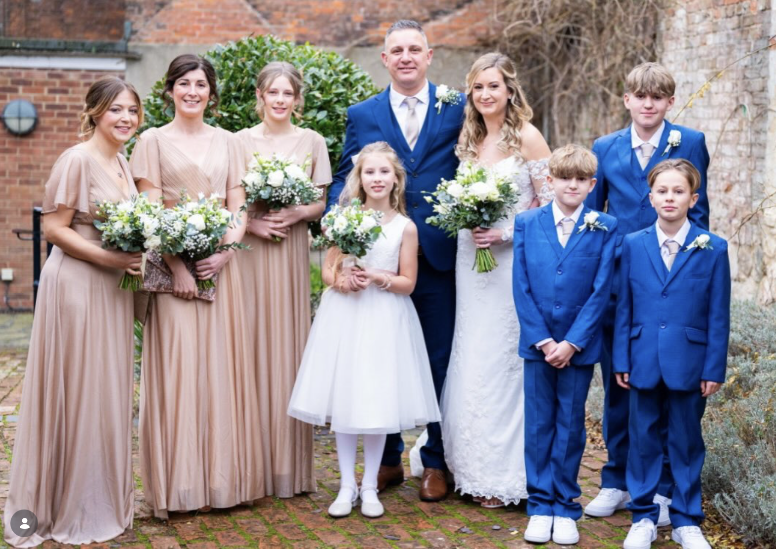 Bride, groom, bridesmaids and page boys holding white rose and eucalyptus bouquets at a Norfolk wedding